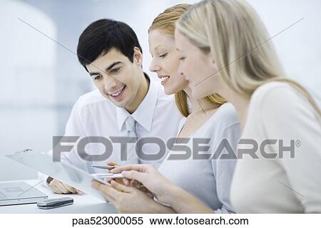 Three colleagues reading document on clipboard, smiling View Large Photo Image Stock Photography - Three colleagues reading document on clipboard, smiling. Fotosearch