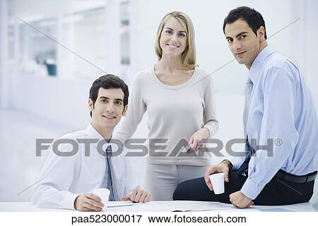 Three professionals taking a coffee break, smiling at camera View Large Photo Image Stock Photo - Three professionals taking a coffee break, smiling at camera. Fotosearch