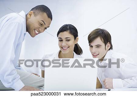 Young professionals looking at laptop computer together, smiling View Large Photo Image Stock Image - Young professionals looking at laptop computer together, smiling. Fotosearch