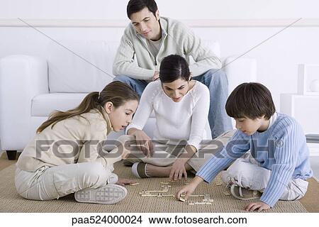 Picture - Family spending time together, mother and children playing dominoes, father watching. Fotosearch