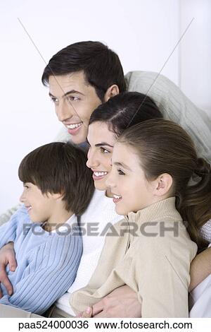 Man embracing his wife and children, all looking away and smiling View Large Photo Image Stock Photograph - Man embracing his wife and children, all looking away and smiling. Fotosearch