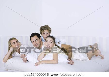 Parents and two children lying in bed together View Large Photo Image Stock Photograph - Parents and two children lying in bed together. Fotosearch