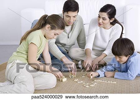 Parents and two children seated on floor, playing dominoes together View Large Photo Image Stock Photo - Parents and two children seated on floor, playing dominoes together. Fotosearch