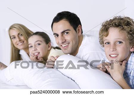 Portrait of family lying in bed together View Large Photo Image Stock Photo - Portrait of family lying in bed together. Fotosearch