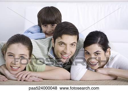 Portrait of smiling family lying together on floor, son lying on his father's back View Large Photo Image Stock Photo - Portrait of smiling family lying together on floor, son lying on his father's back. Fotosearch