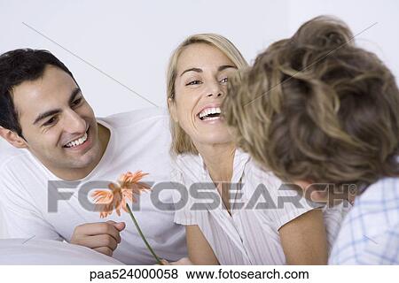 Woman laughing with husband and son, holding flower View Large Photo Image Stock Photo - Woman laughing with husband and son, holding flower. Fotosearch