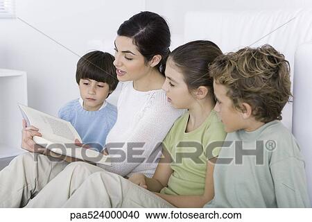 Stock Image - Woman reading story to her children. Fotosearch