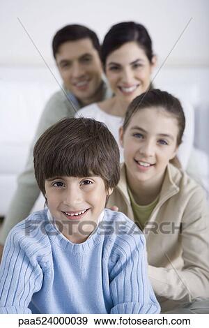 Stock Photo - Young boy sitting with his family behind him, smiling, portrait. Fotosearch