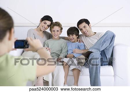 Young girl taking photo of her parents and brothers sitting together on sofa View Large Photo Image Stock Image - Young girl taking photo of her parents and brothers sitting together on sofa. Fotosearch