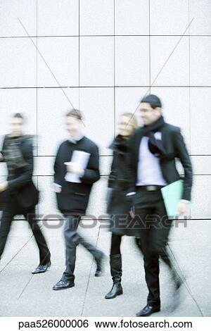 Business associates walking together down sidewalk View Large Photo Image Stock Photograph - Business associates walking together down sidewalk. Fotosearch
