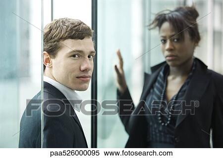 Businessman and businesswoman looking at camera with uncertainty View Large Photo Image Stock Photography - Businessman and businesswoman looking at camera with uncertainty. Fotosearch