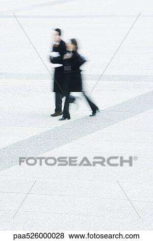 Businessman and businesswoman walking together across public square View Large Photo Image Stock Photo - Businessman and businesswoman walking together across public square. Fotosearch