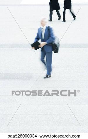 Businessman carrying briefcase crossing public square View Large Photo Image Picture - Businessman carrying briefcase crossing public square. Fotosearch
