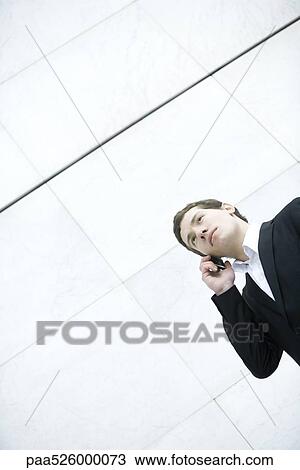 Businessman talking on cell phone, low angle view View Large Photo Image Stock Image - Businessman talking on cell phone, low angle view. Fotosearch