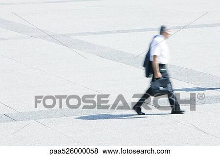 Businessman with jacket on shoulder walking across public square View Large Photo Image Stock Photo - Businessman with jacket on shoulder walking across public square. Fotosearch