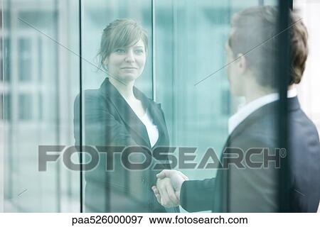 Businesswoman and businessman meet and shake hands at building entrance View Large Photo Image Stock Photo - Businesswoman and businessman meet and shake hands at building entrance. Fotosearch