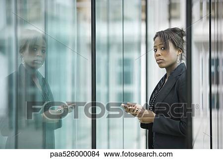 Businesswoman using cell phone, looking at camera View Large Photo Image Picture - Businesswoman using cell phone, looking at camera. Fotosearch