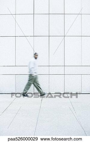 Man walking with hands in his pockets down sidewalk View Large Photo Image Stock Photo - Man walking with hands in his pockets down sidewalk. Fotosearch
