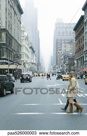Stock Image - Pedestrians crossing street in crosswalk at W 19th Street and 6th Avenue Chelsea, New York, facing NE. Fotosearch
