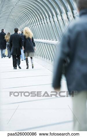 Pedestrians walking across elevated walkway View Large Photo Image Stock Photograph - Pedestrians walking across elevated walkway. Fotosearch