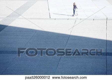 Small child riding push scooter alone in public square View Large Photo Image Stock Image - Small child riding push scooter alone in public square. Fotosearch