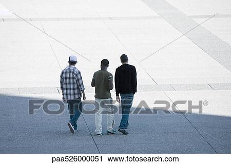 Three young men walking together across public square View Large Photo Image Stock Image - Three young men walking together across public square. Fotosearch