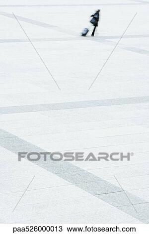 Woman walking across public square pulling rolling suitcase behind her View Large Photo Image Stock Image - Woman walking across public square pulling rolling suitcase behind her . Fotosearch
