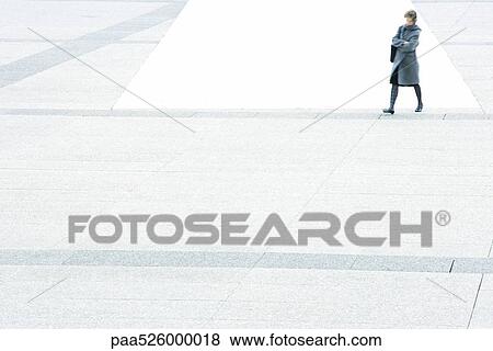 Stock Photo - Woman with arms folded walking across city square. Fotosearch