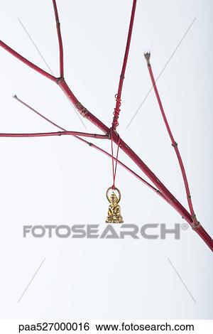 Miniature Buddha ornament hanging from bare branch View Large Photo Image Stock Photograph - Miniature Buddha ornament hanging from bare branch. Fotosearch