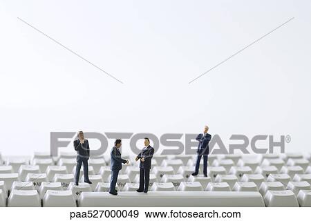 Stock Photo - Miniature businessmen negotiating on computer keyboard. Fotosearch