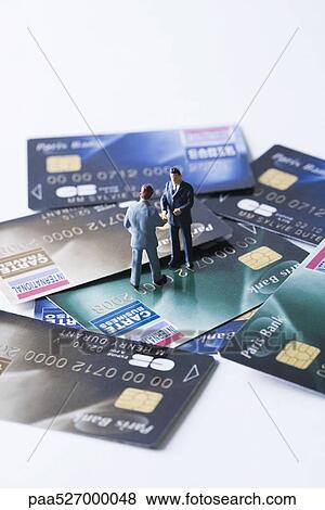 Miniature businessmen shaking hands on pile of credit cards View Large Photo Image Stock Photo - Miniature businessmen shaking hands on pile of credit cards. Fotosearch