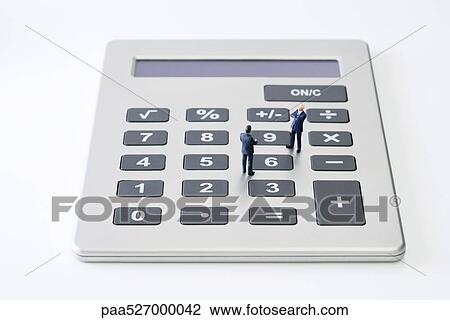 Stock Image - Miniature businessmen standing face to face on calculator. Fotosearch