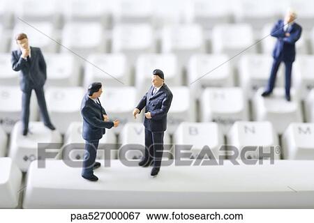 Miniature businessmen standing face to face on computer keyboard View Large Photo Image Stock Photo - Miniature businessmen standing face to face on computer keyboard. Fotosearch