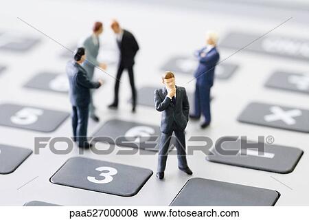 Miniature businessmen standing on calculator View Large Photo Image Stock Photo - Miniature businessmen standing on calculator. Fotosearch