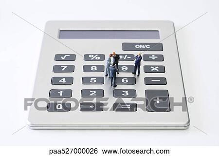 Stock Photograph - Miniature businessmen standing on calculator. Fotosearch