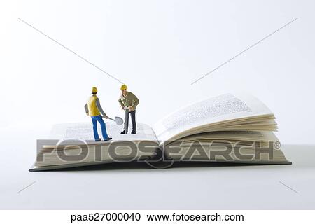 Miniature construction workers standing on open book View Large Photo Image Stock Image - Miniature construction workers standing on open book. Fotosearch