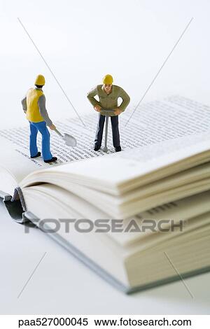 Miniature construction workers standing on open book View Large Photo Image Stock Photography - Miniature construction workers standing on open book. Fotosearch