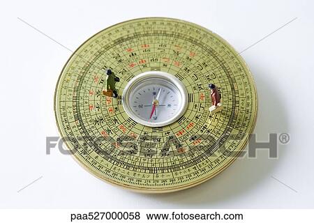 Stock Photo - Miniature figures walking on Feng Shui compass. Fotosearch