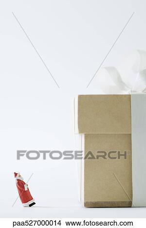 Miniature Santa Claus looking at large gift, side view View Large Photo Image Picture - Miniature Santa Claus looking at large gift, side view. Fotosearch