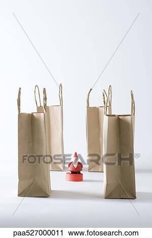 Santa Claus figurine surrounded by paper shopping bags View Large Photo Image Stock Image - Santa Claus figurine surrounded by paper shopping bags. Fotosearch