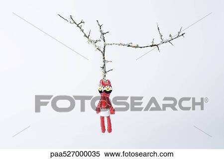 Stock Photography - Strange doll hanging on bare branch. Fotosearch