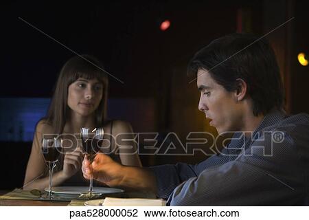 Couple having serious conversation over dinner at restaurant, man picking up glass of wine View Large Photo Image Stock Image - Couple having serious conversation over dinner at restaurant, man picking up glass of wine. Fotosearch