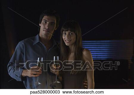Couple holding glasses of champagne, smiling at camera, portrait View Large Photo Image Stock Image - Couple holding glasses of champagne, smiling at camera, portrait. Fotosearch