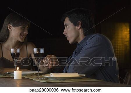 Couple holding hands during romantic dinner, looking at each other View Large Photo Image Stock Photograph - Couple holding hands during romantic dinner, looking at each other. Fotosearch