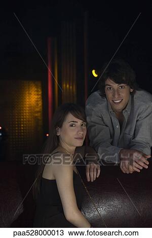 Stock Image - Couple in nightclub, smiling at camera, portrait. Fotosearch