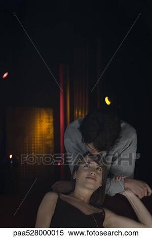 Couple, woman sitting, man standing behind leaning forward, kissing her on forehead View Large Photo Image Stock Photography - Couple, woman sitting, man standing behind leaning forward, kissing her on forehead. Fotosearch