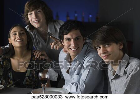 Stock Image - Friends in a bar, smiling at camera, portrait. Fotosearch