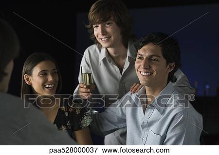 Stock Photo - Friends laughing, one holding glass of champagne. Fotosearch
