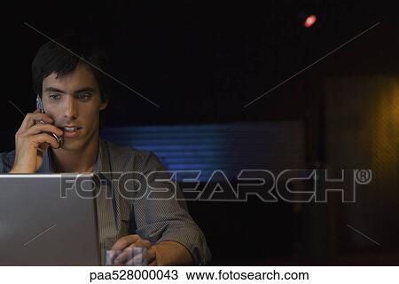 Man talking on cell phone, using laptop computer View Large Photo Image Stock Image - Man talking on cell phone, using laptop computer. Fotosearch