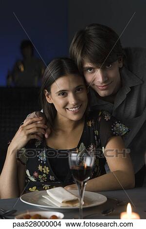Picture - Portrait of couple at restaurant, holding hands, smiling at camera. Fotosearch